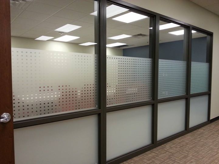 Glass-walled office with frosted lower panels and a wooden door in a hallway