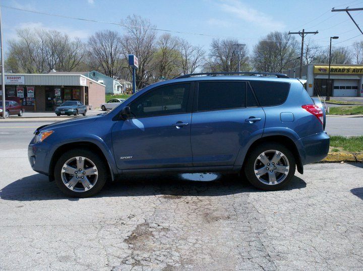 Blue SUV parked beside a road on a sunny day