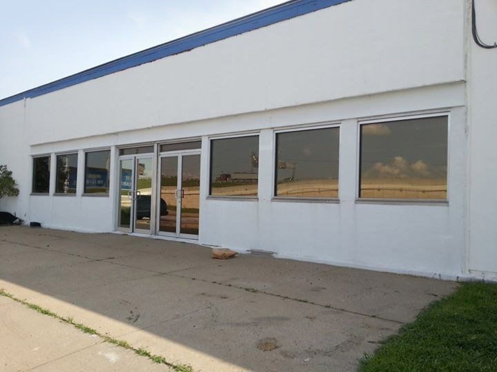 White storefront exterior with glass doors and windows along a concrete sidewalk