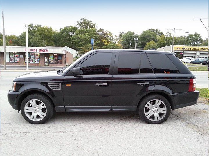 Black SUV parked in a lot, side view with tinted windows and silver rims