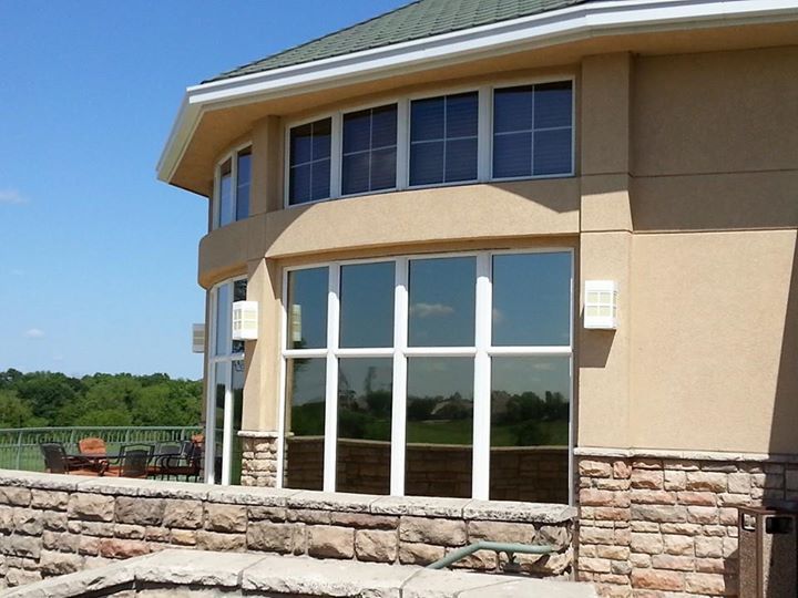Curved beige building with large glass windows and stone facade under a clear blue sky