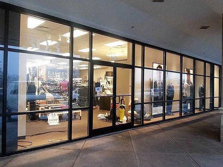 Glass storefront windows along a covered walkway, showing a brightly lit shop interior