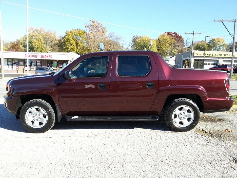 Maroon pickup truck parked on a sunny street in front of shops