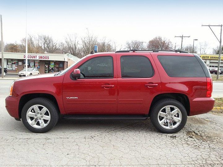 Red SUV parked in a lot, side view, with tinted windows and silver wheels.
