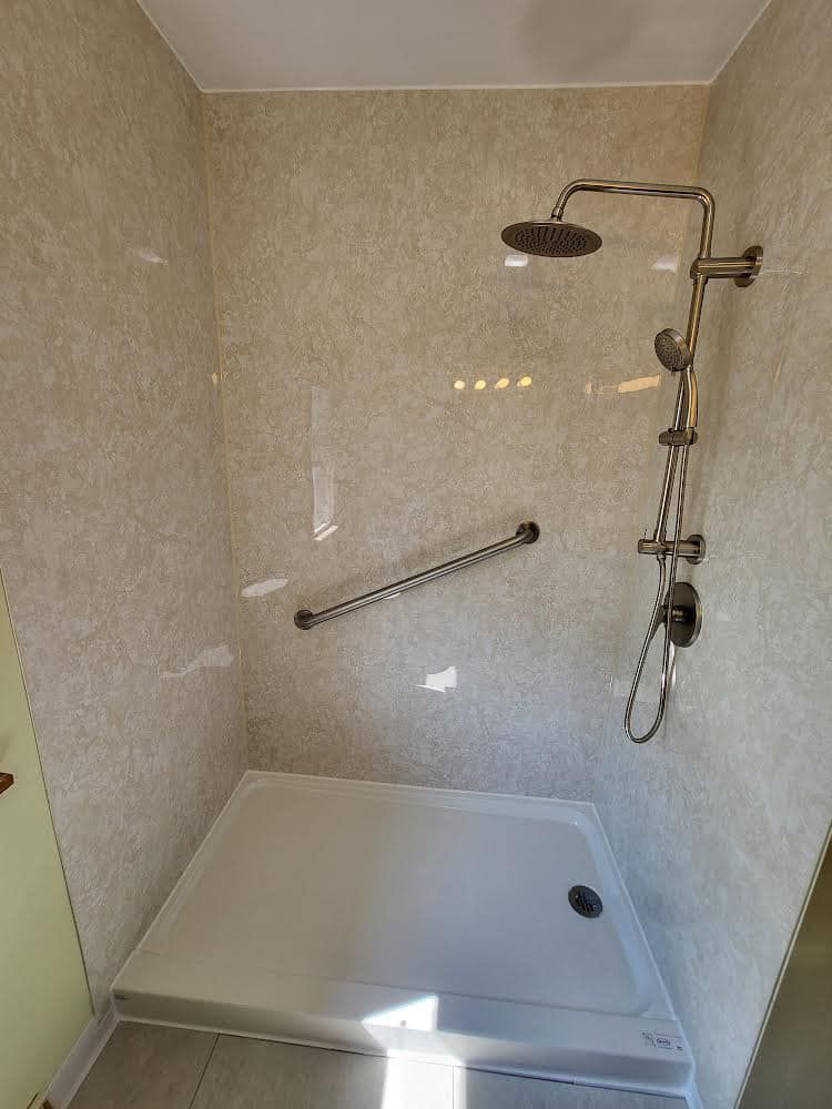 Accessible shower stall with grab bar and shower head.