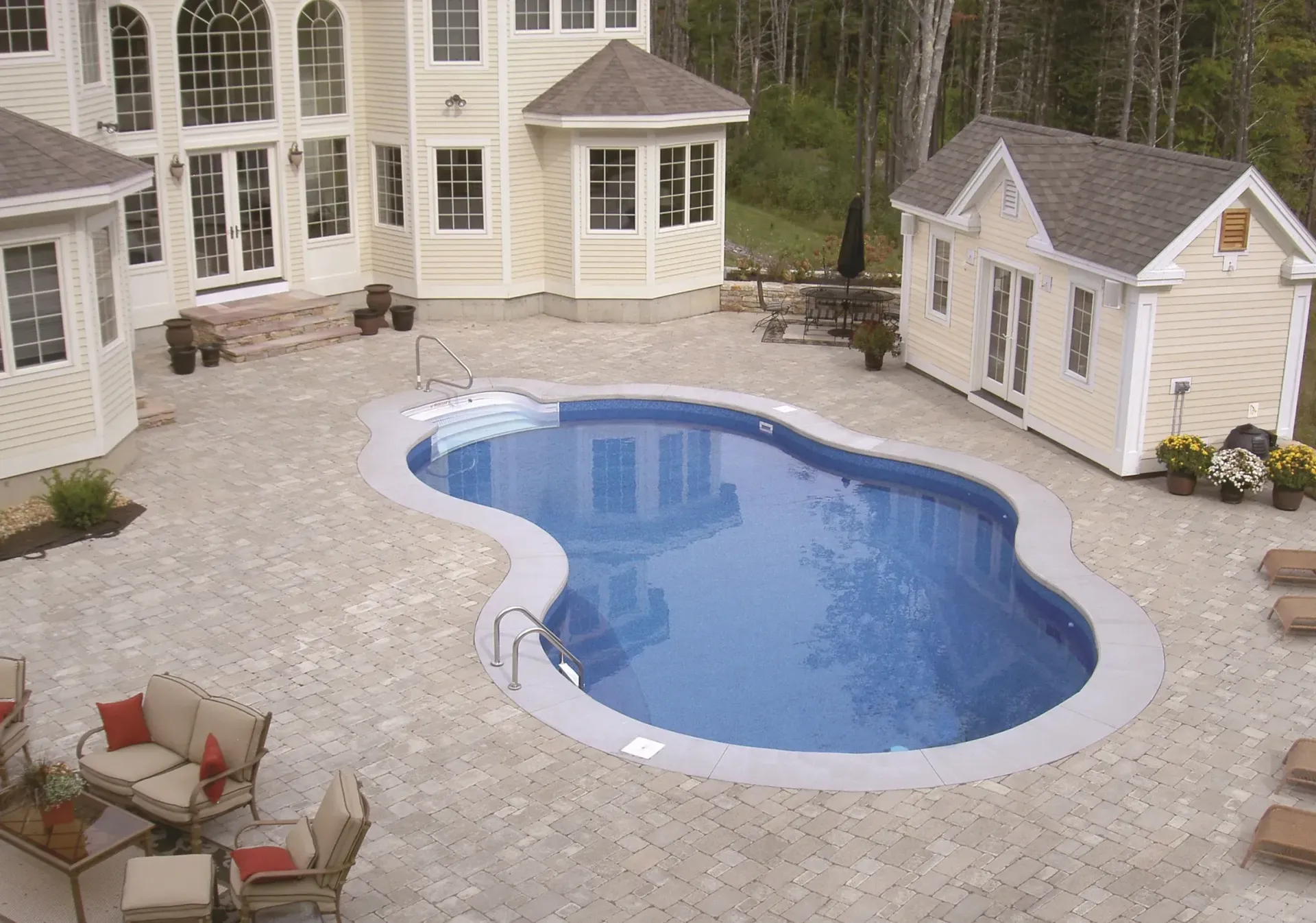 Backyard with a pool, patio, house, and small shed, mostly beige, blue pool water.