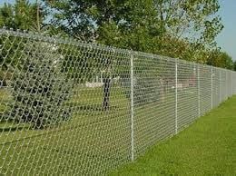 a chain link fence is sitting on top of a lush green field