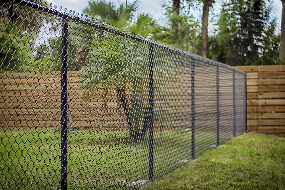 a chain link fence with a wooden fence behind it