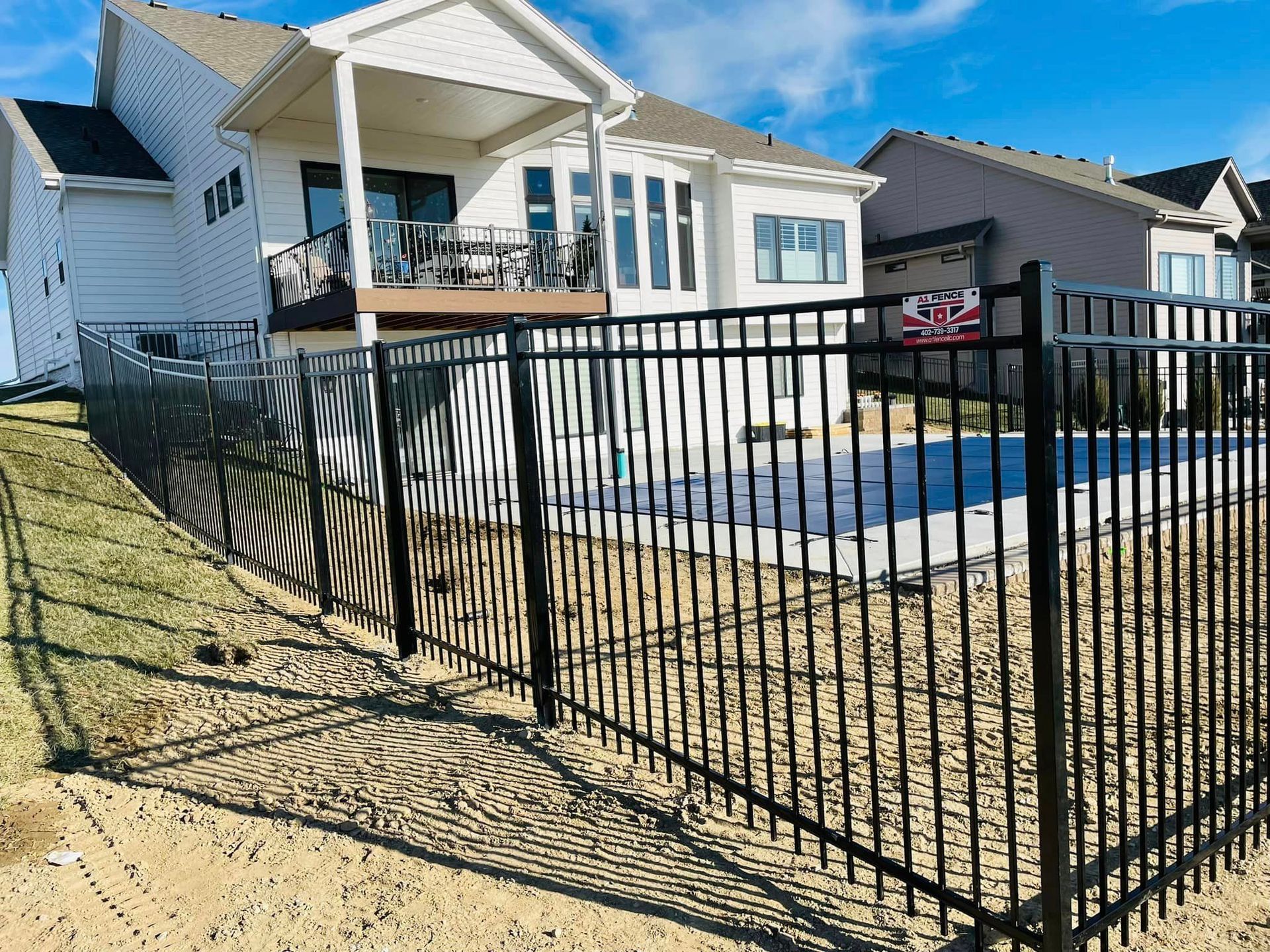 a black fence surrounds a swimming pool in front of a house