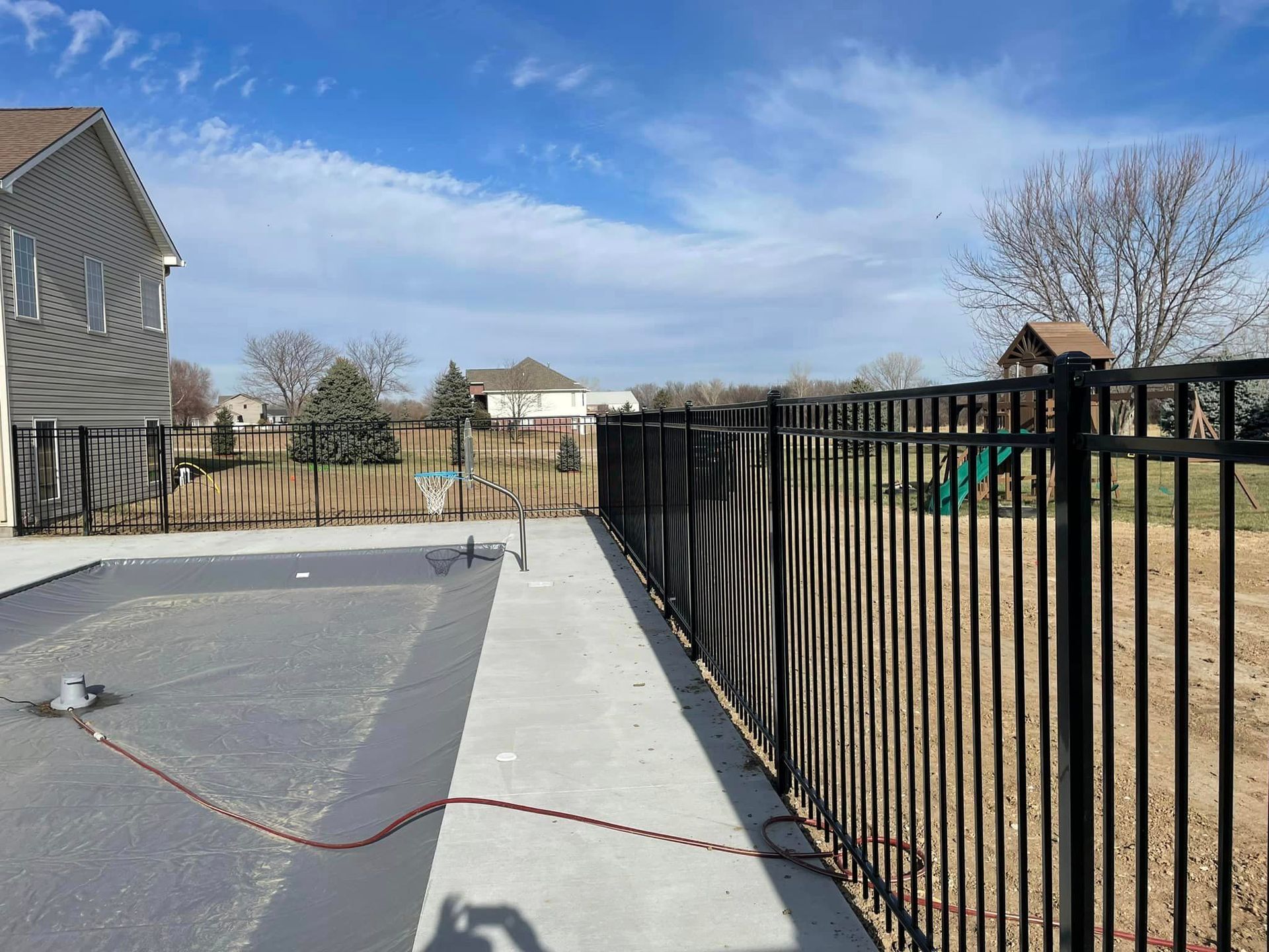 a black fence surrounds a yard with a basketball ring
