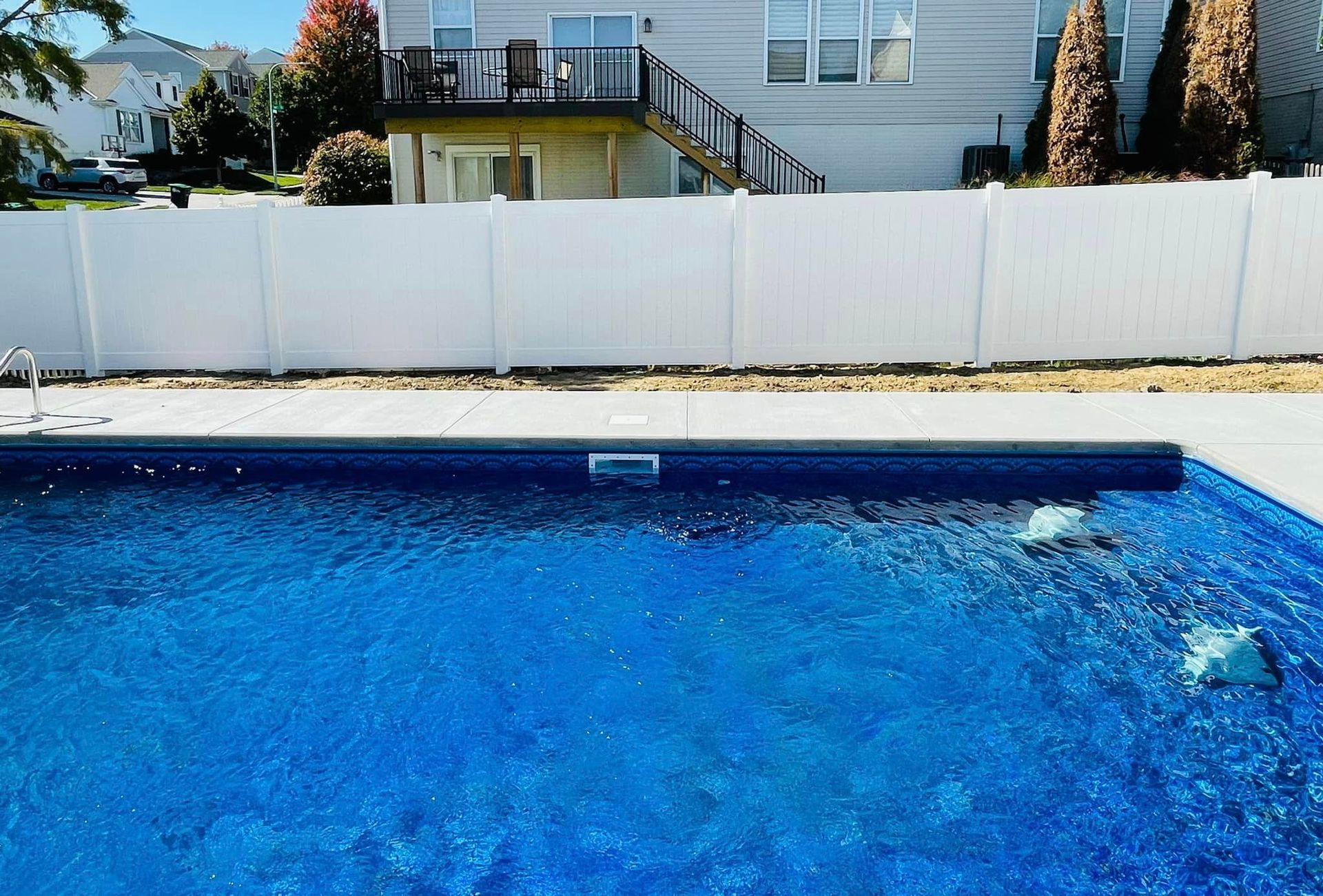 a white fence surrounds a large swimming pool