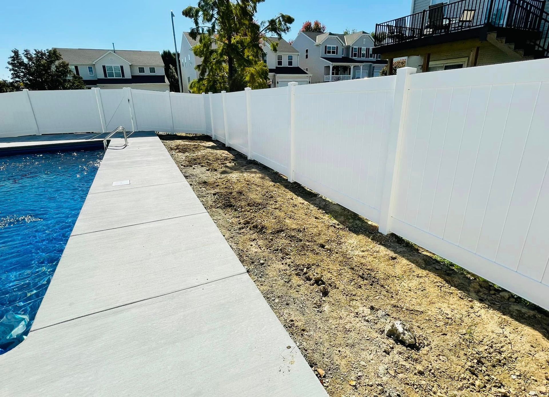 a white fence surrounds a swimming pool in a backyard