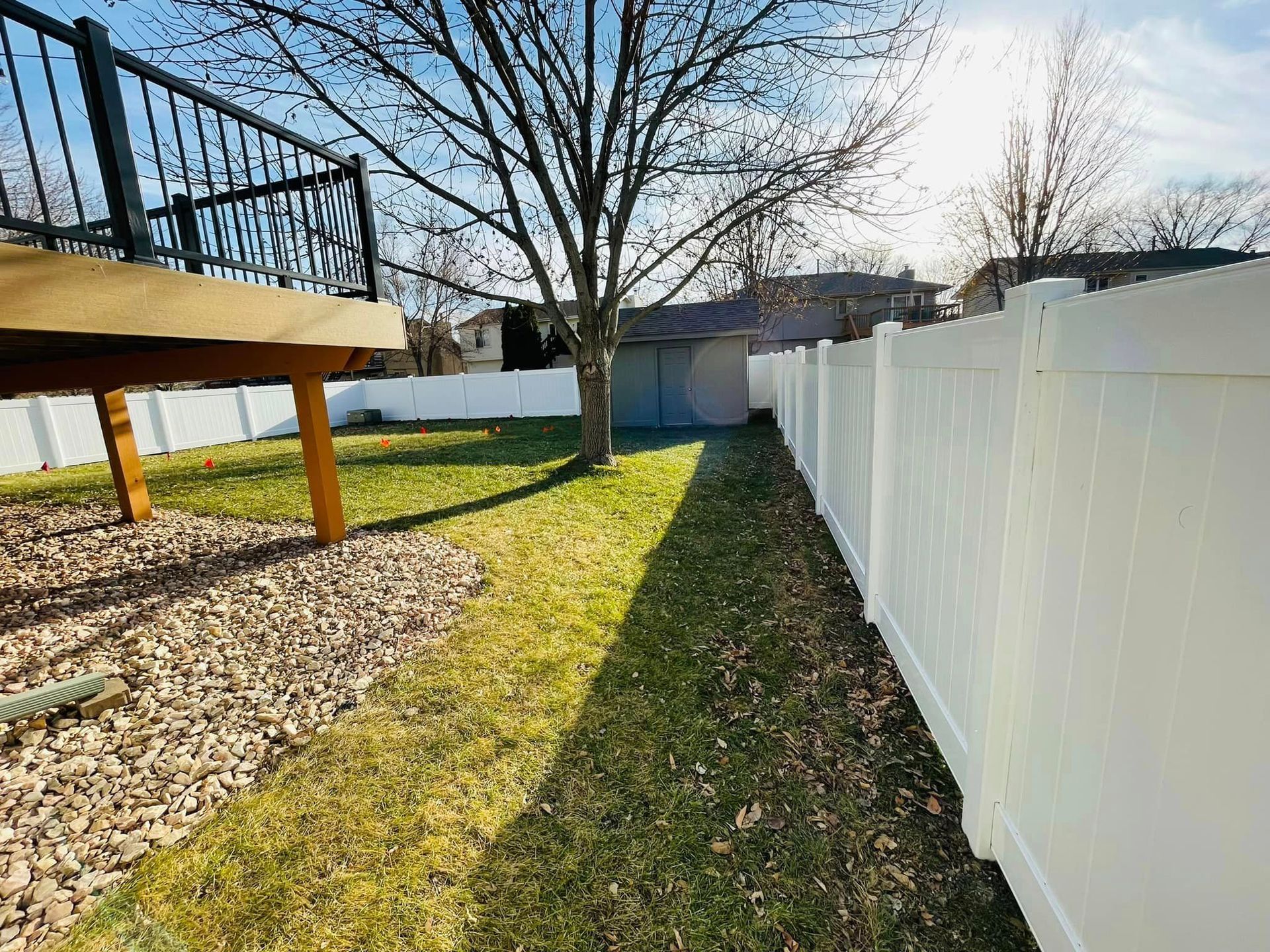 a white fence surrounds the backyard of a house with a deck