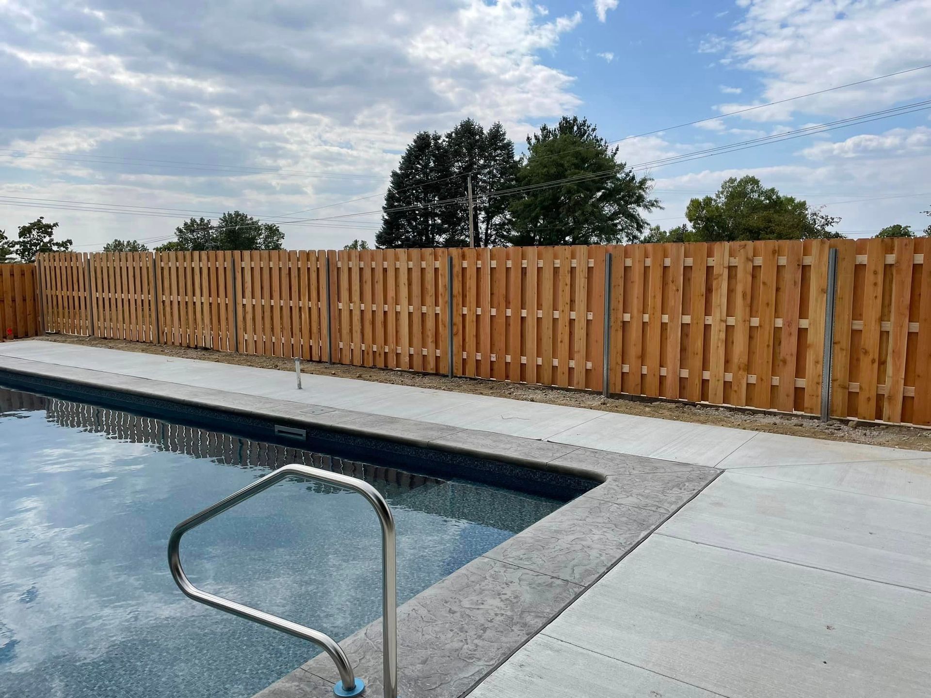 a wooden fence surrounds a large swimming pool