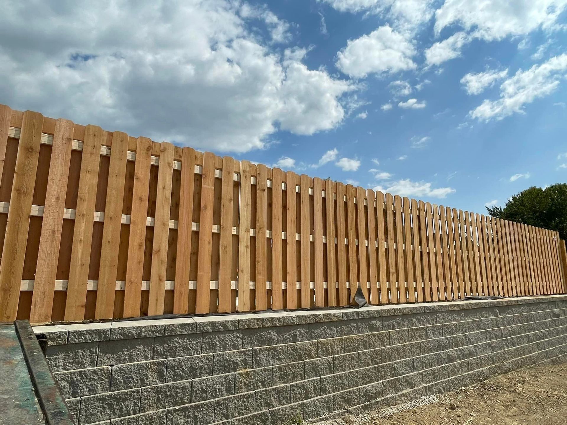 a wooden fence surrounds a brick wall on a sunny day