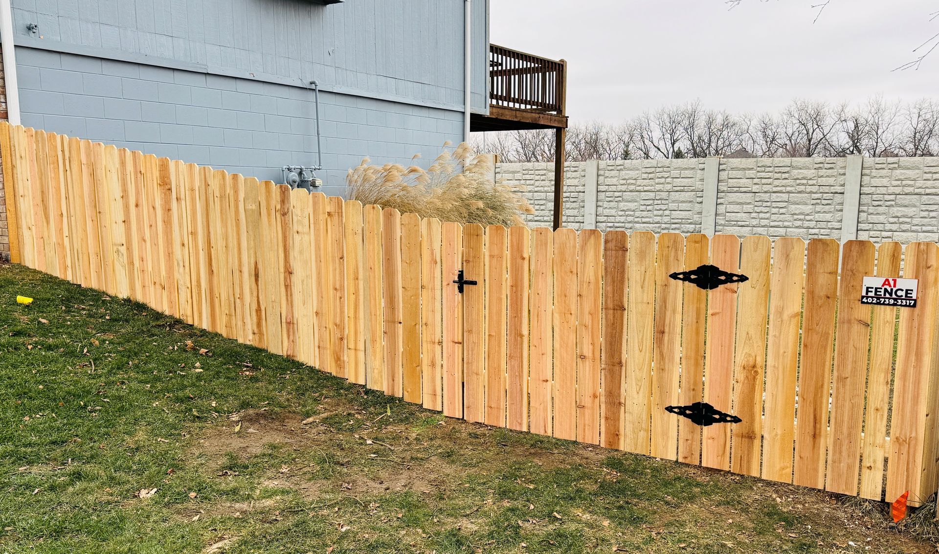 Wooden fence on a slight incline, with a gate and a house in the background.