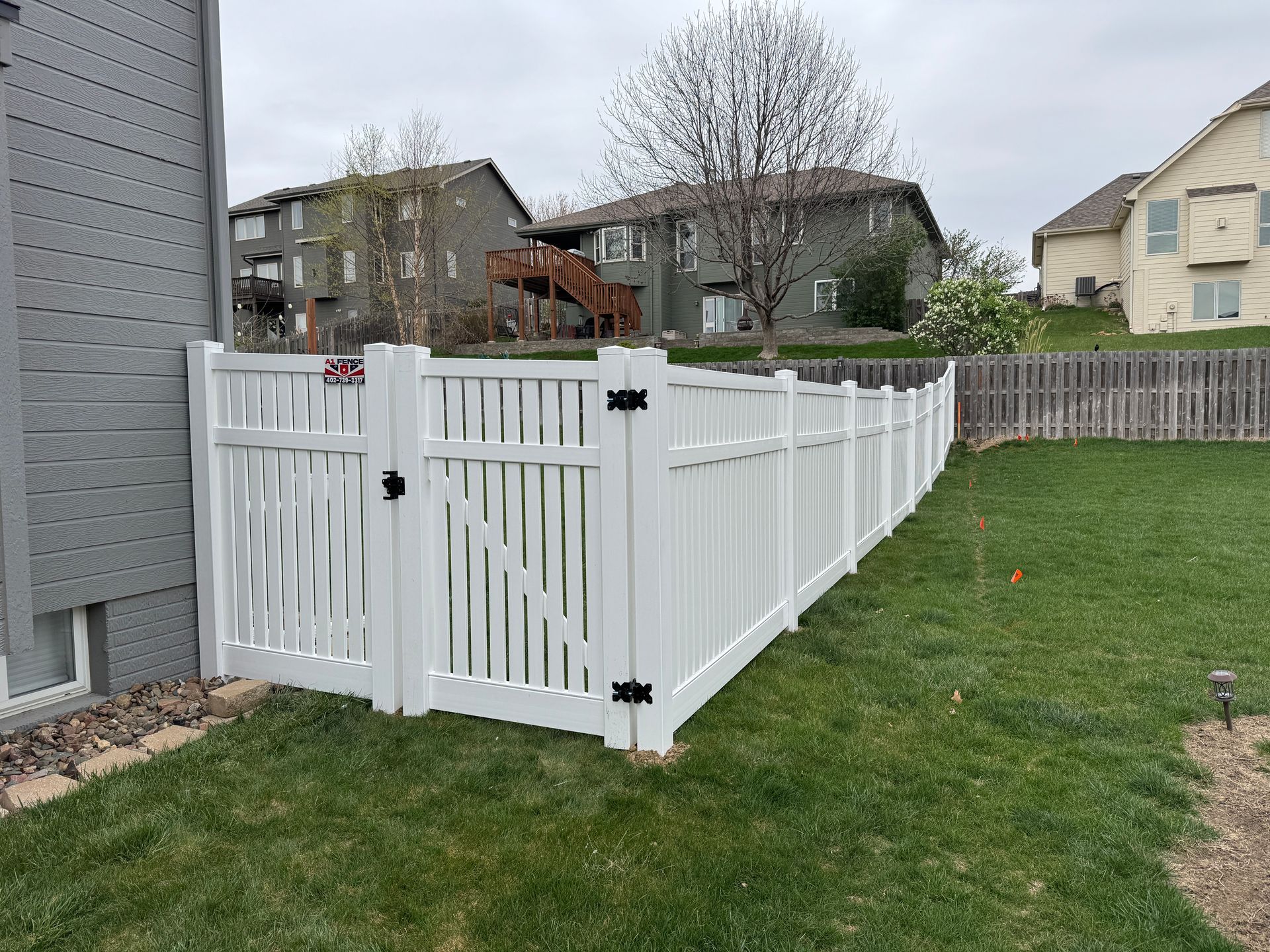 White vinyl fence with gate in residential yard.