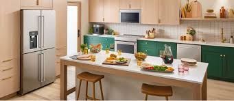 A kitchen with stainless steel appliances , green cabinets , and a large island.