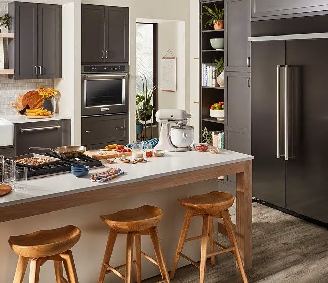 A kitchen with a table , stools , and a refrigerator.