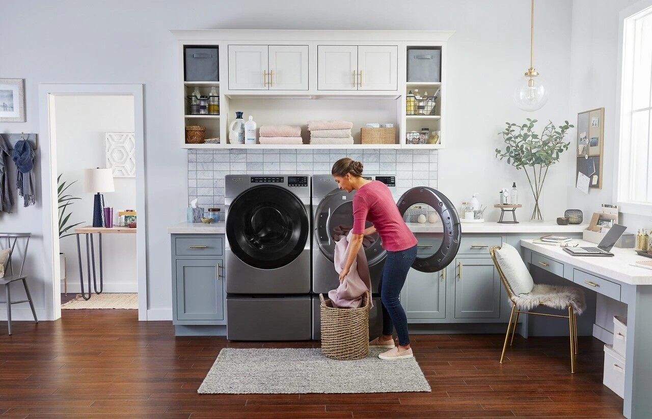 A woman is doing laundry in a laundry room with a washer and dryer.