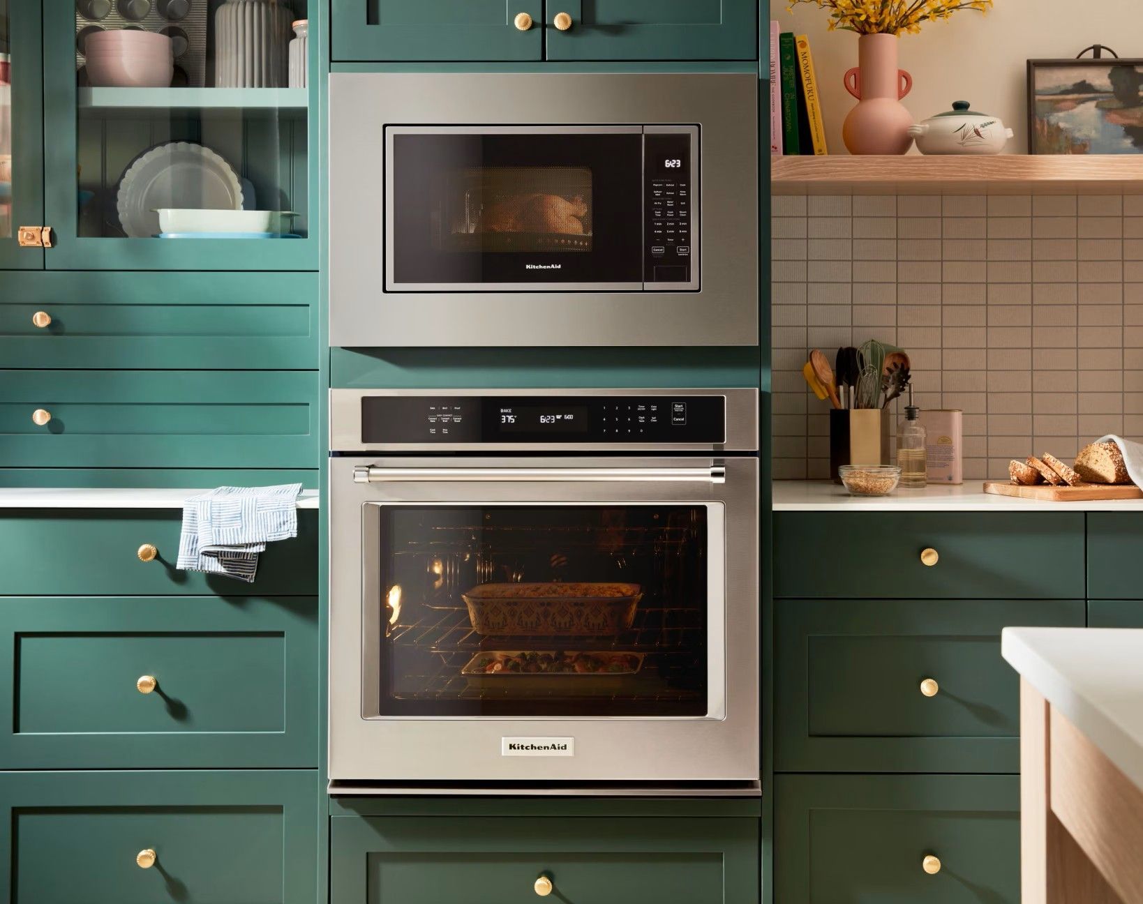 A kitchen with green cabinets and a stainless steel oven and microwave.