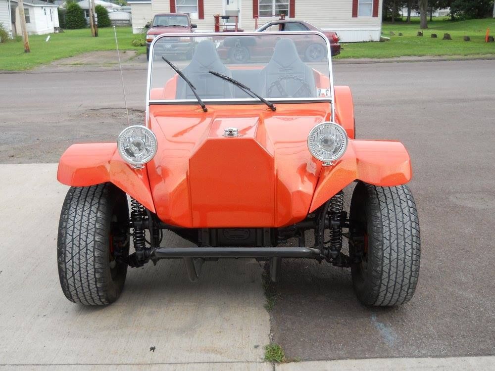 Orange dune buggy parked on a driveway, front view with round headlights and windshield wipers