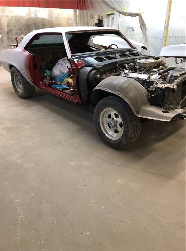 Partially restored classic car in a garage, front end exposed with no hood or grille