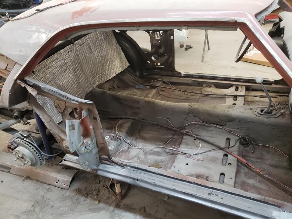 Rusty stripped car body with exposed interior and missing windows in a workshop
