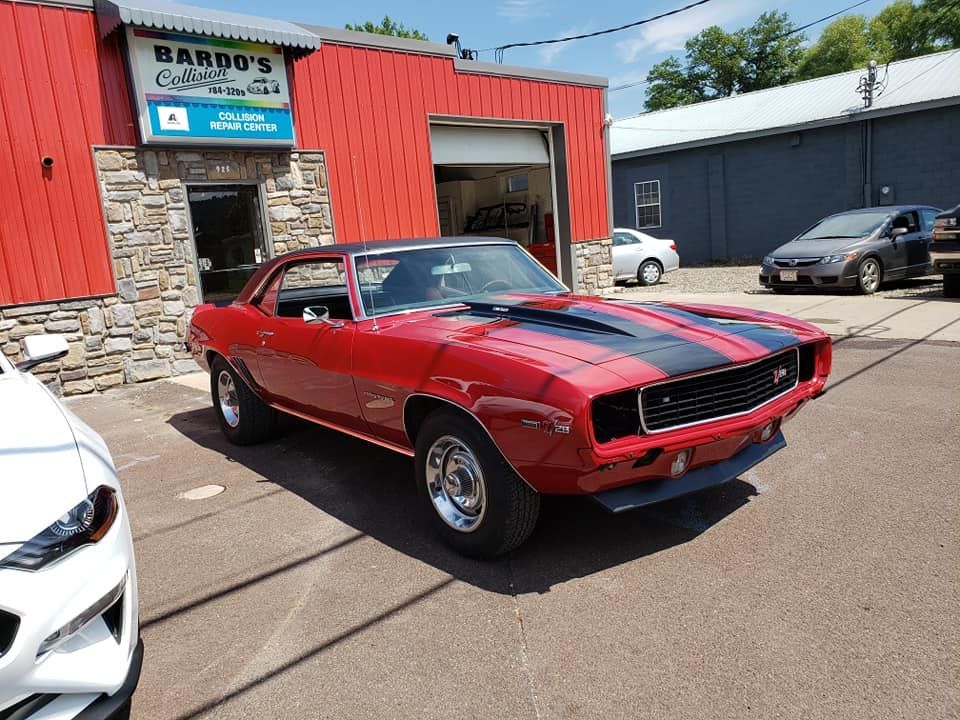 Red classic muscle car parked outside an auto shop on a sunny day