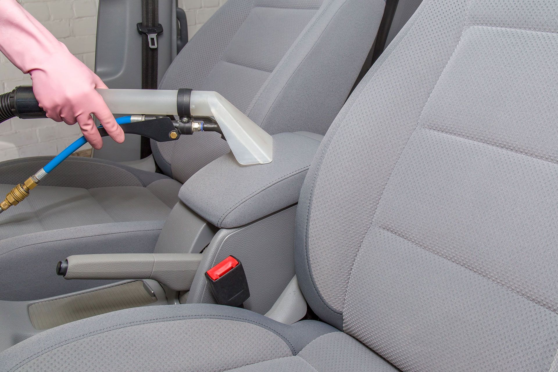 A person is cleaning the seats of a car with a vacuum cleaner.