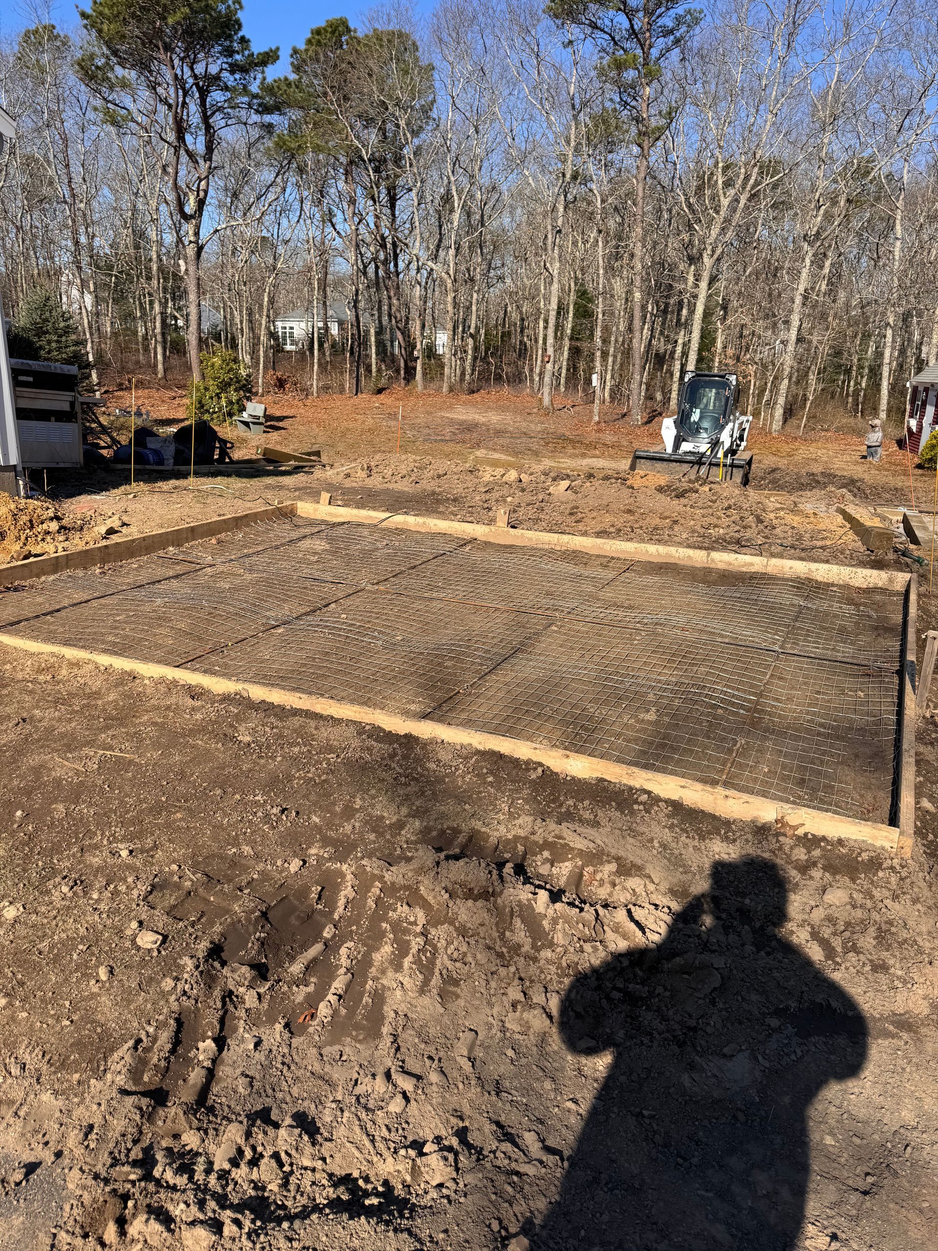 A shadow of a person is cast on a muddy field.