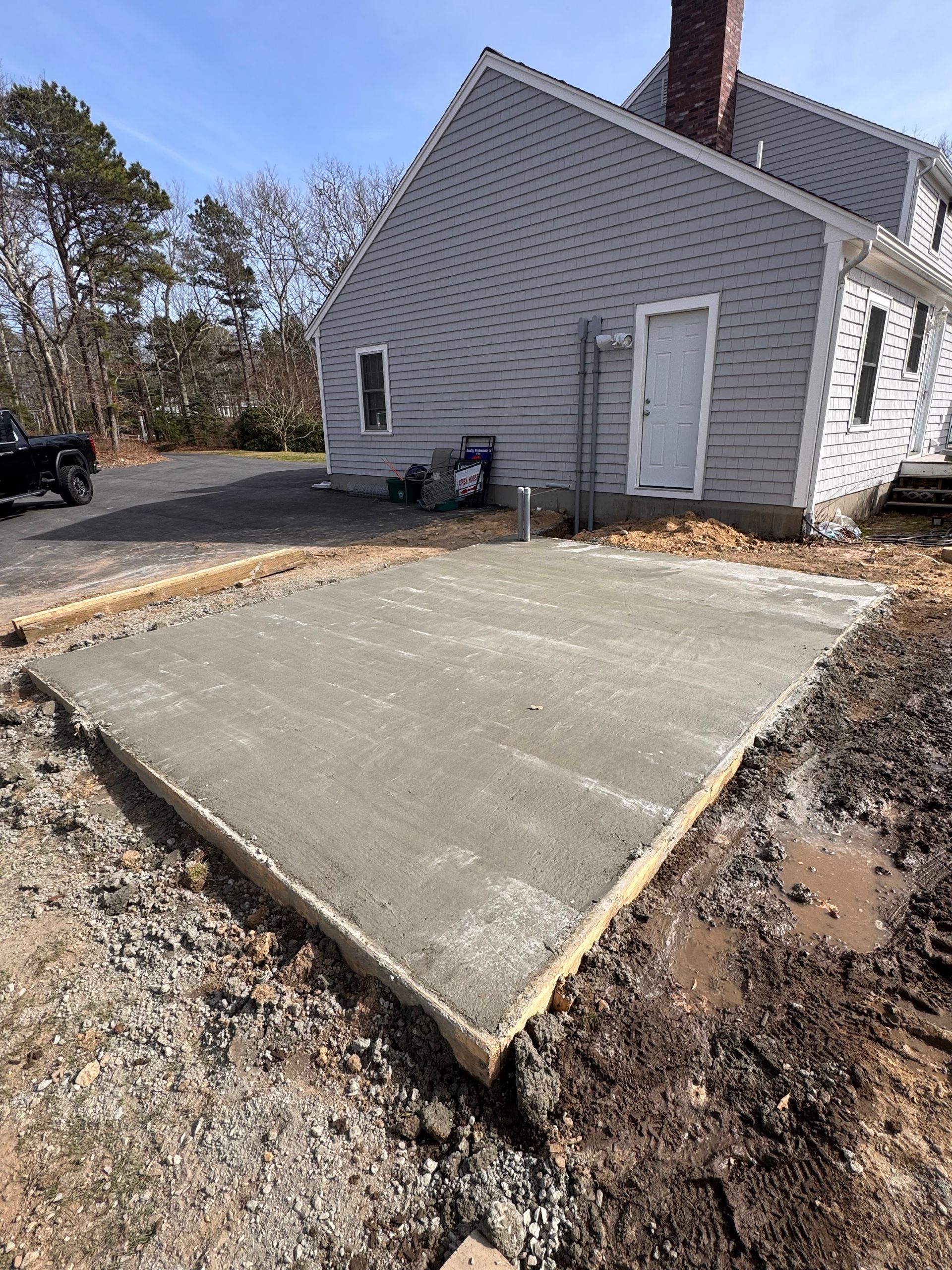 A concrete driveway is being built in front of a house.