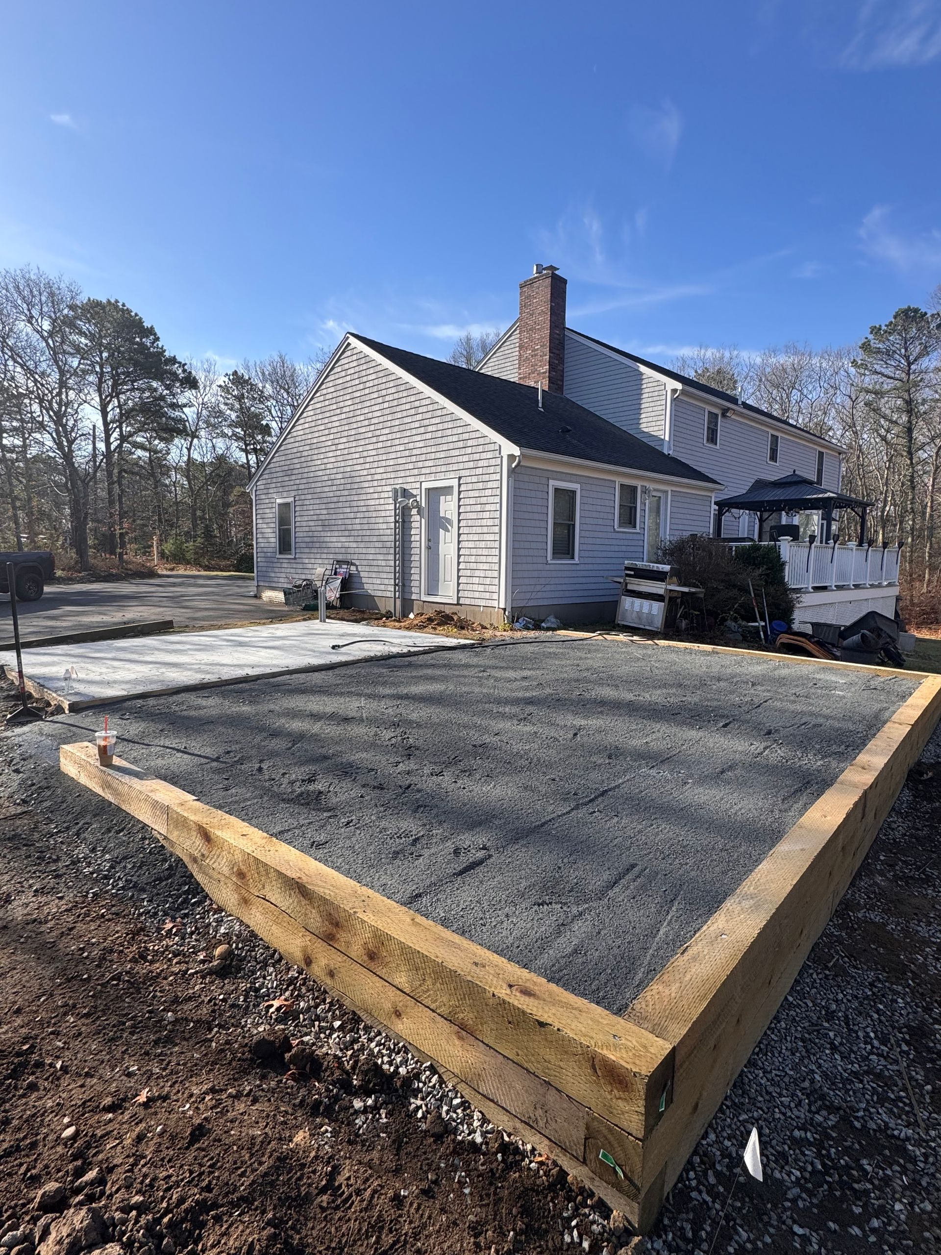 A white house with a gravel driveway in front of it.