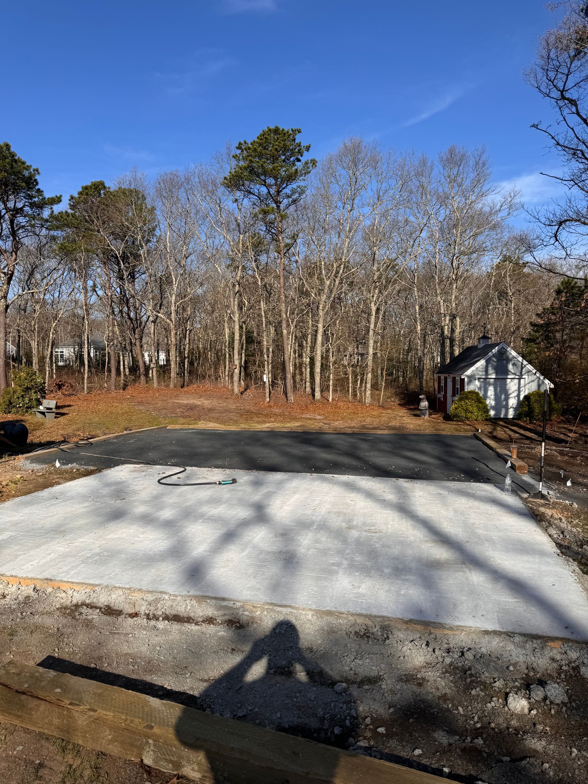 A concrete driveway with a house in the background and trees in the background.