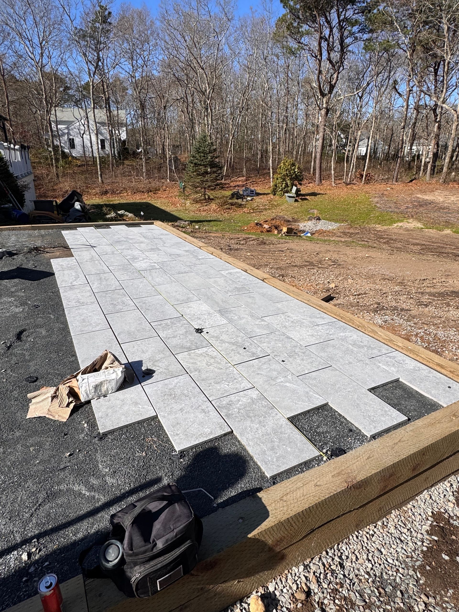 A concrete walkway is being built in a yard with trees in the background.