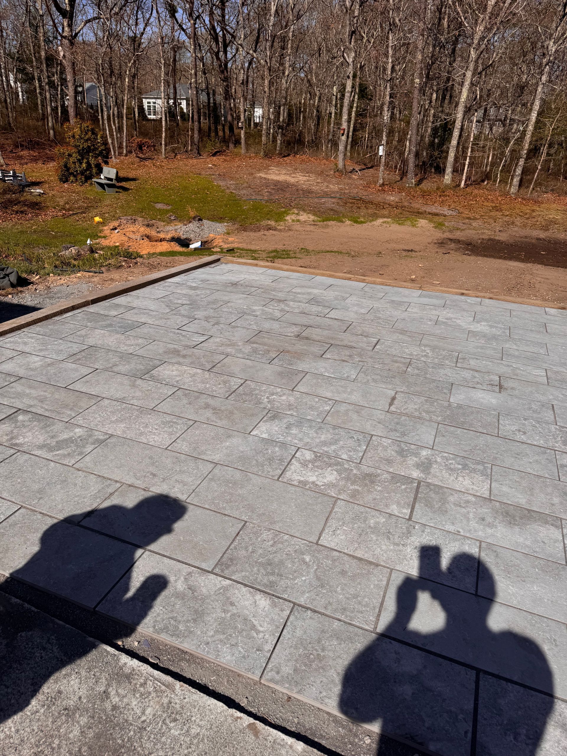 A person is taking a picture of their shadow on a patio.