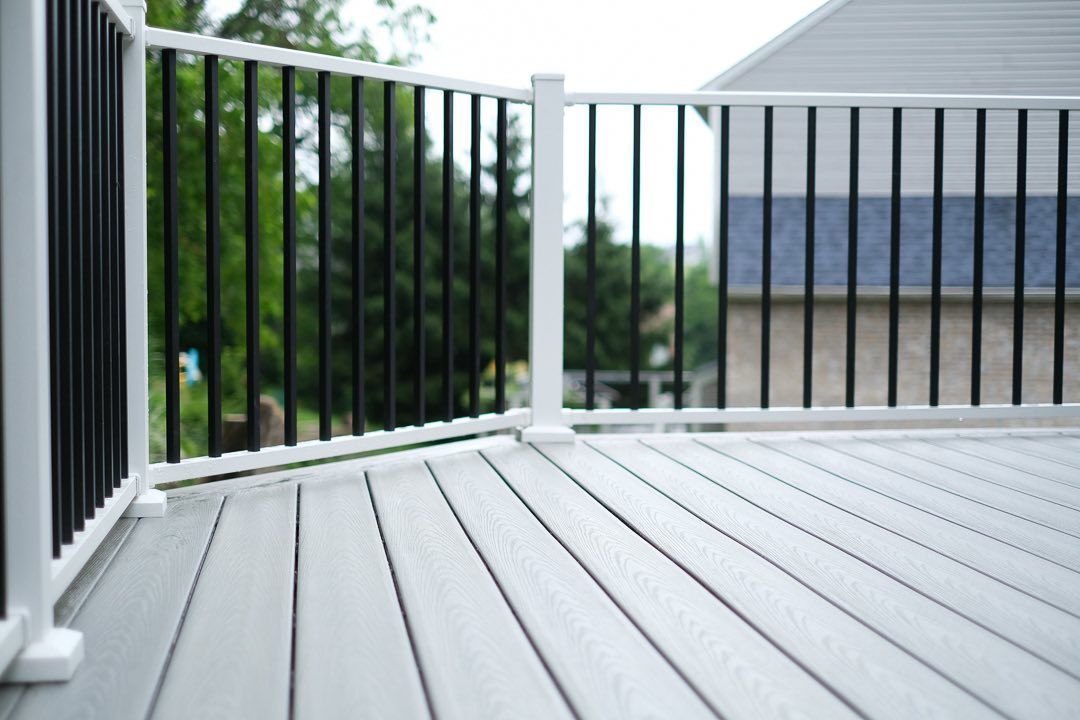 Gray composite deck with white railings and black vertical bars, outdoors.