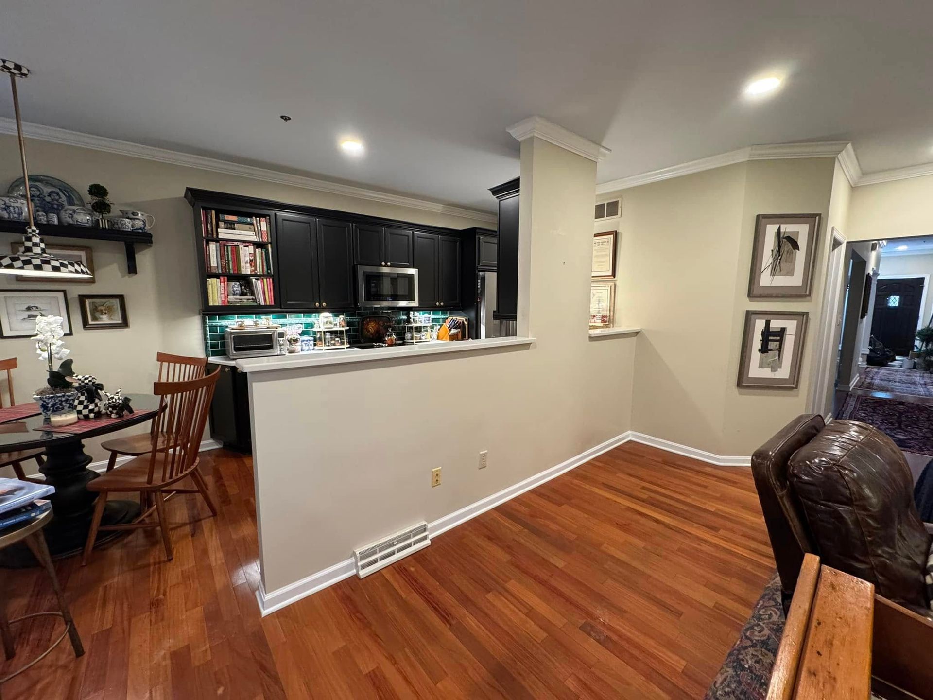 Interior view of a kitchen and dining area with hardwood floors, dark cabinets, and a partially open wall.