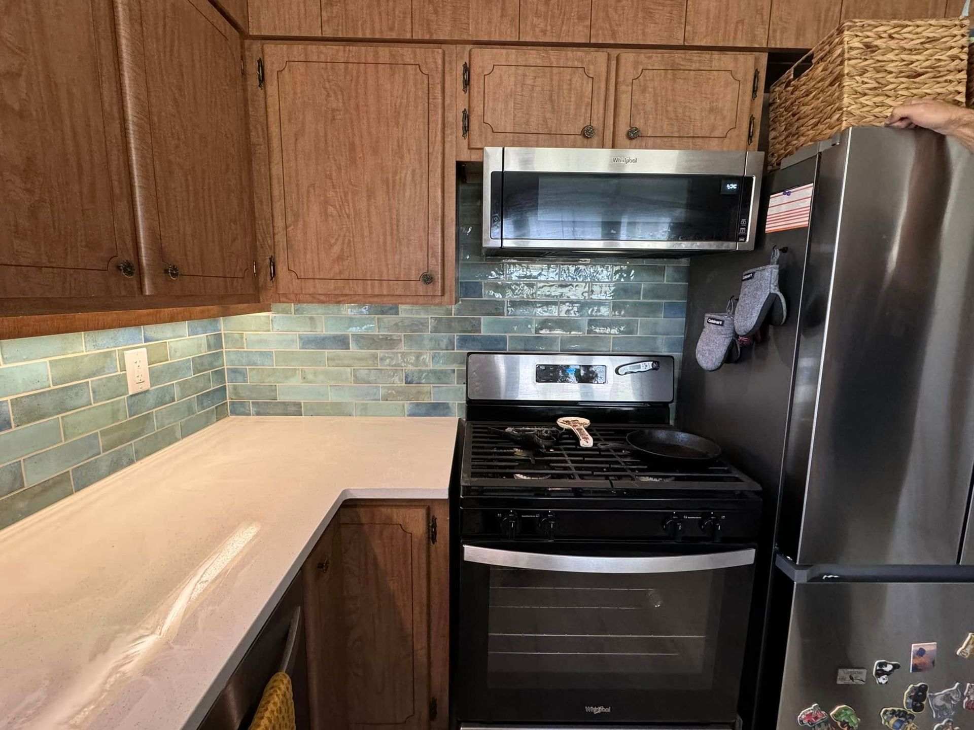 Kitchen with wooden cabinets, teal backsplash, and stainless steel appliances.