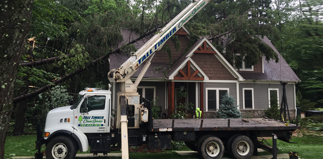 A white truck with a crane attached to it is parked in front of a house.