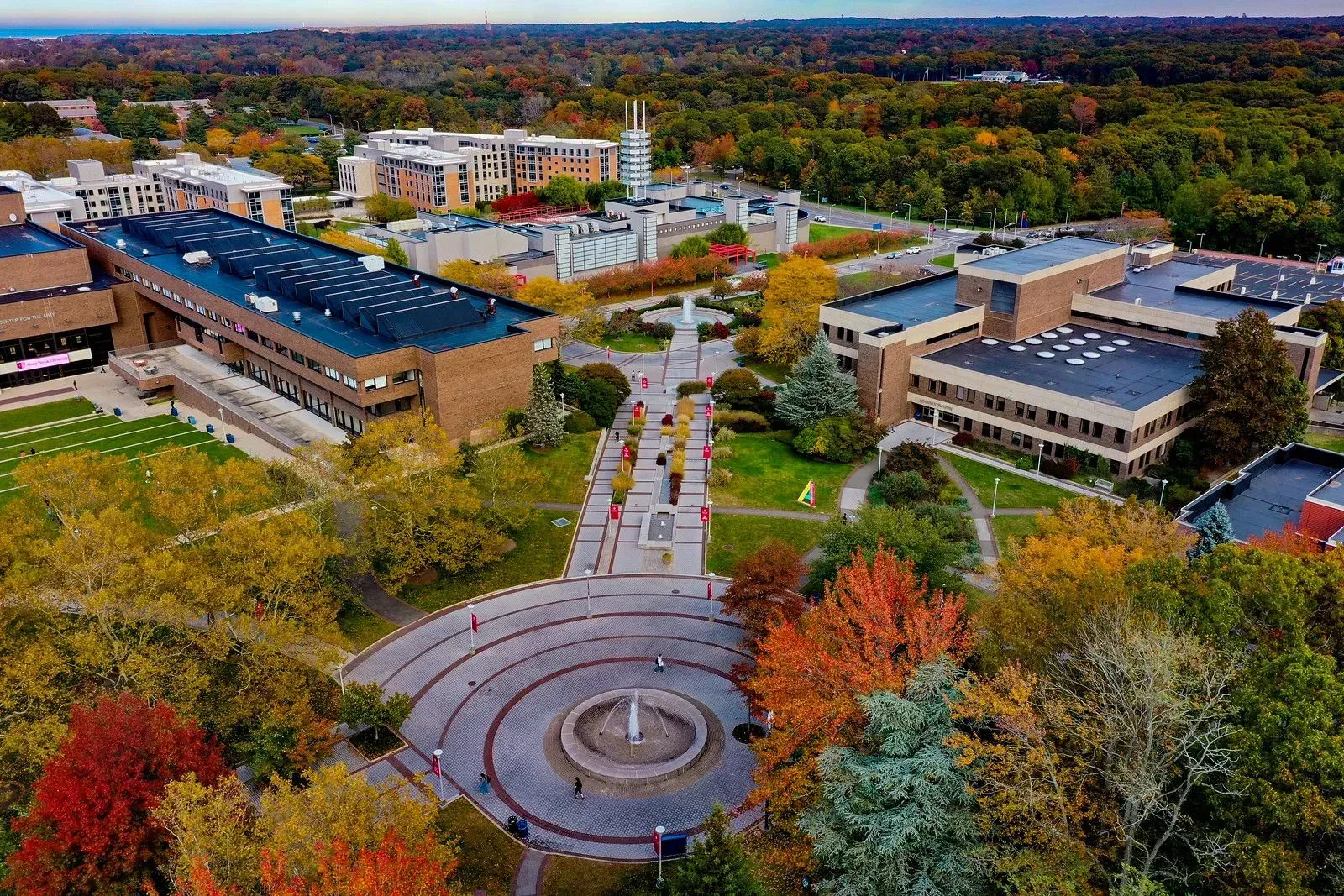 Aerial view of a campus quad with autumn trees, circular plaza, and buildings under a clear sky