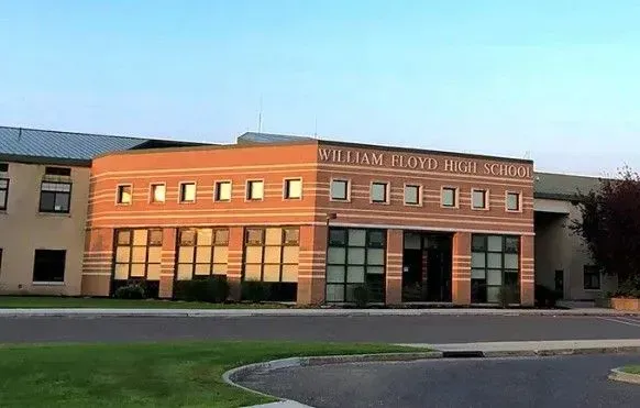Modern brick school building with large windows and a curved driveway in front