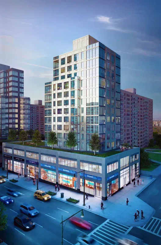 Modern mixed-use high-rise with illuminated storefronts at dusk on a city street.