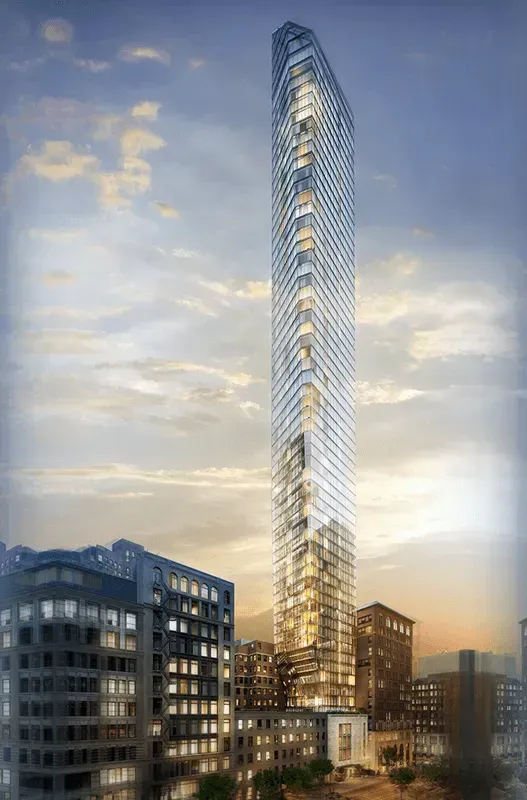 Tall modern glass skyscraper at sunset beside shorter office buildings under a partly cloudy sky