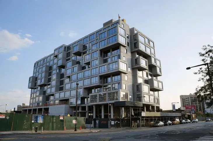 Modern multi-story glass-and-concrete building on a street corner under a blue sky