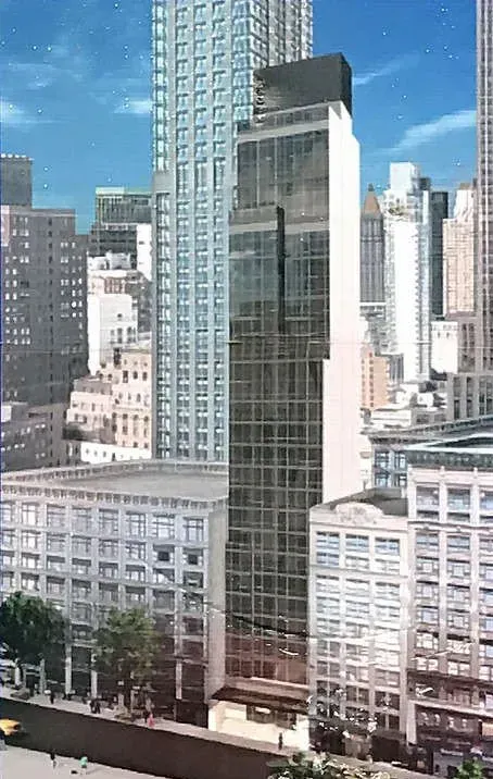 City skyline with a tall glass office tower between low-rise buildings under a blue sky.