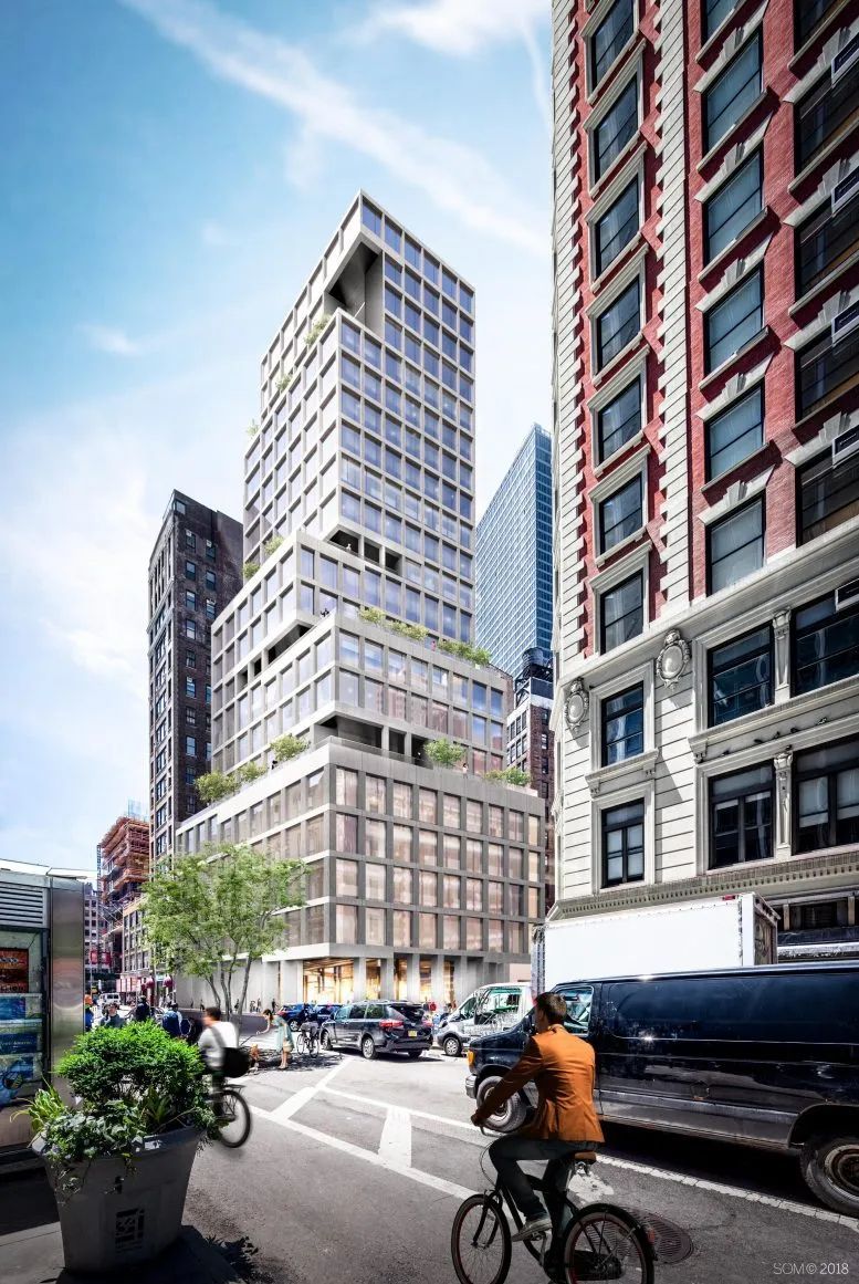 City street with tall modern buildings, a cyclist in an orange jacket, and cars under a blue sky