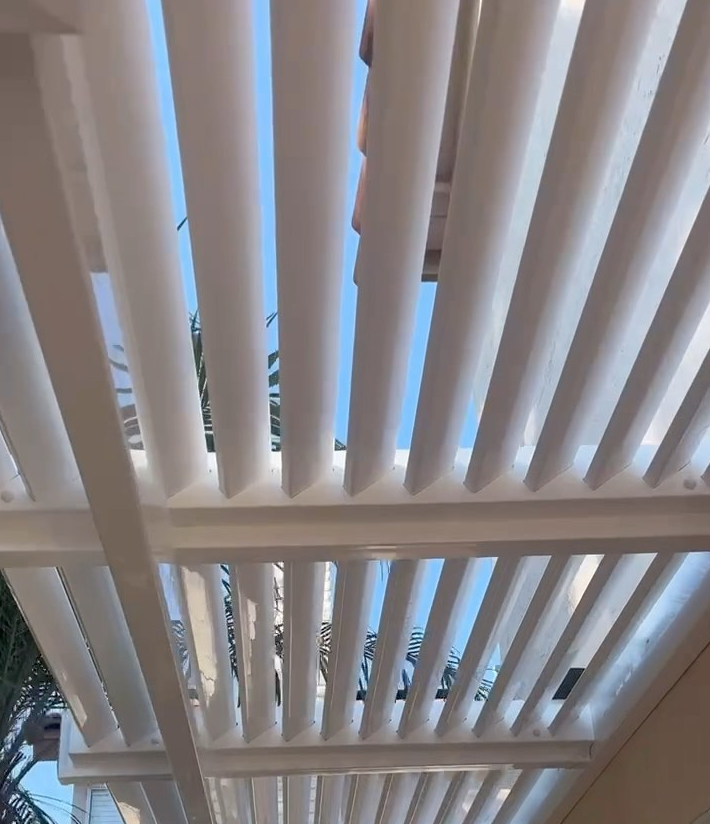 White, slatted pergola roof with a clear blue sky visible through the gaps.