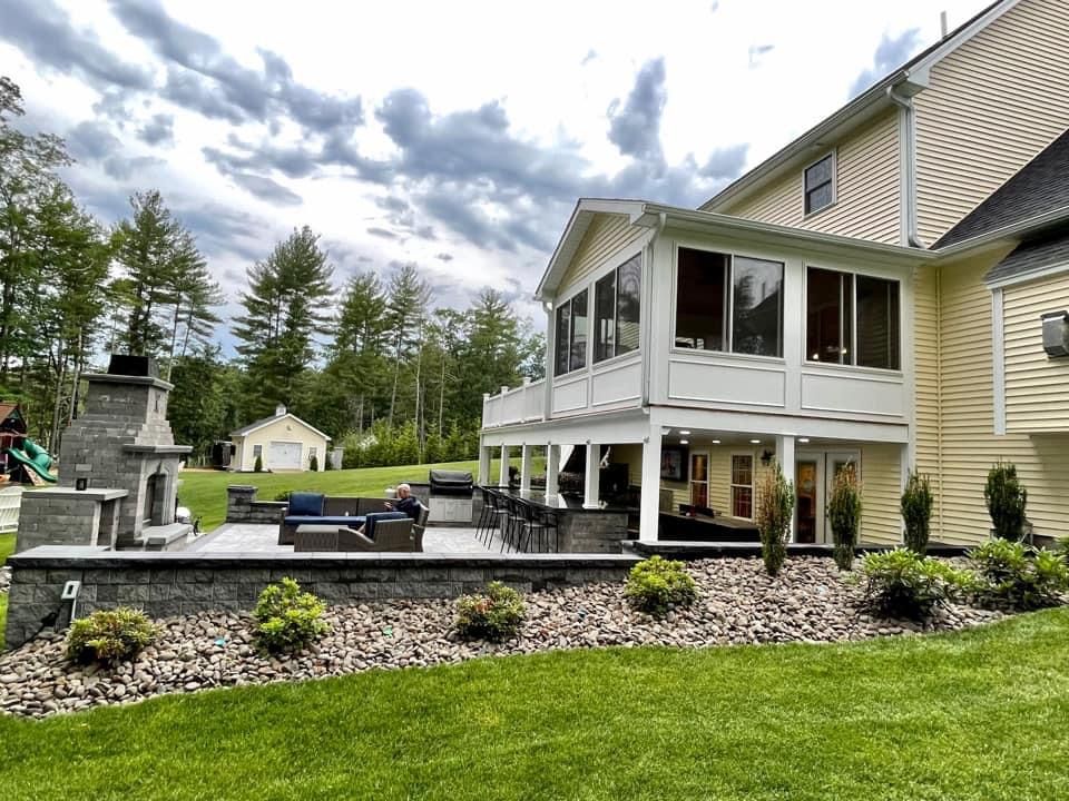 A large house with a screened in porch and a fireplace in the backyard.