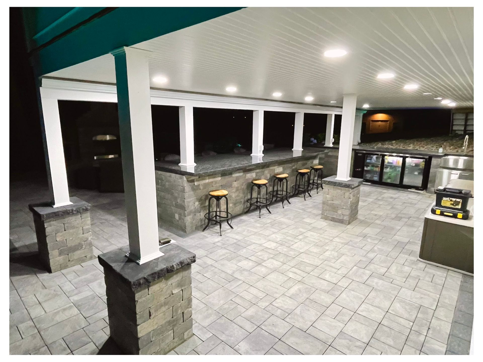 A patio with a bar and stools under a canopy at night.
